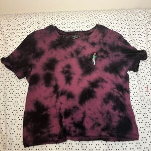 A purple and black tie dye shirt with a skull hand holding a rose.